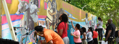 People painting a mural depicting folks on a carousel ride.