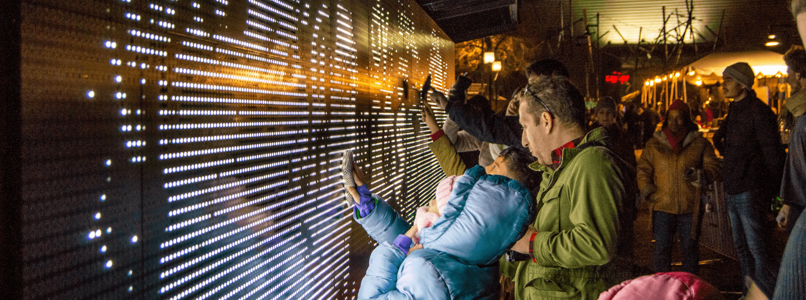 A group of people interacting with an outdoor light installation