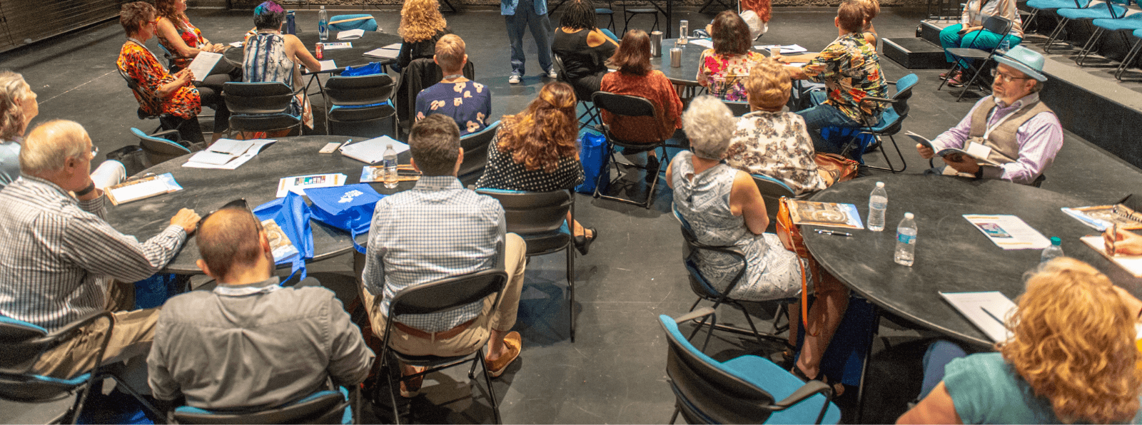 A room of seated people facing forward looking at a presentation