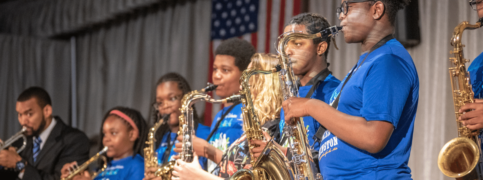 A row of youths play brass instruments on stage