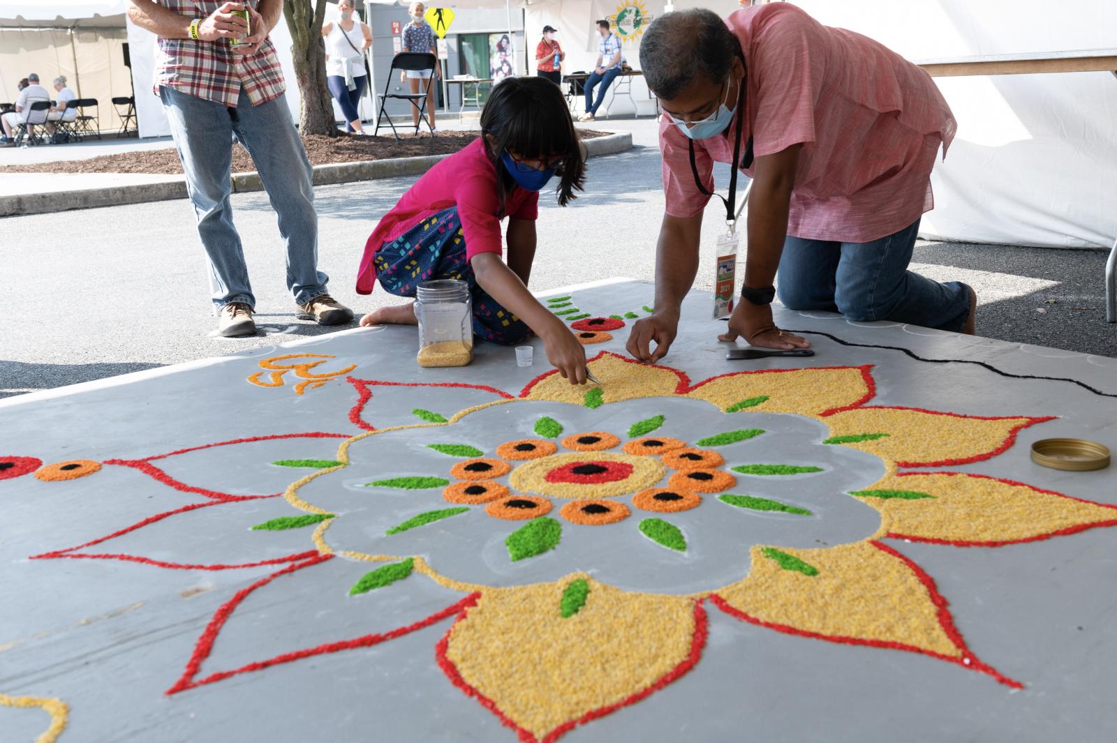 Adult and child drawing a flower on the sidewalk