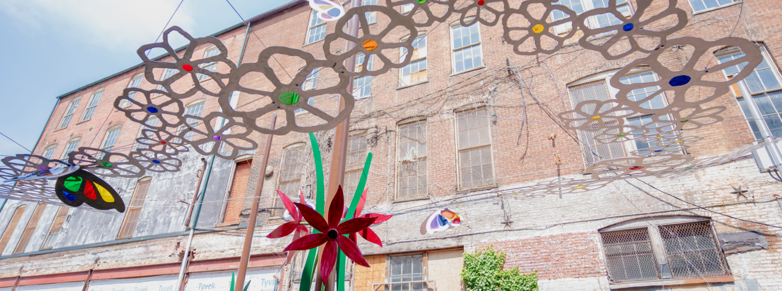 A hanging flower sculpture installation in front of a brick building.
