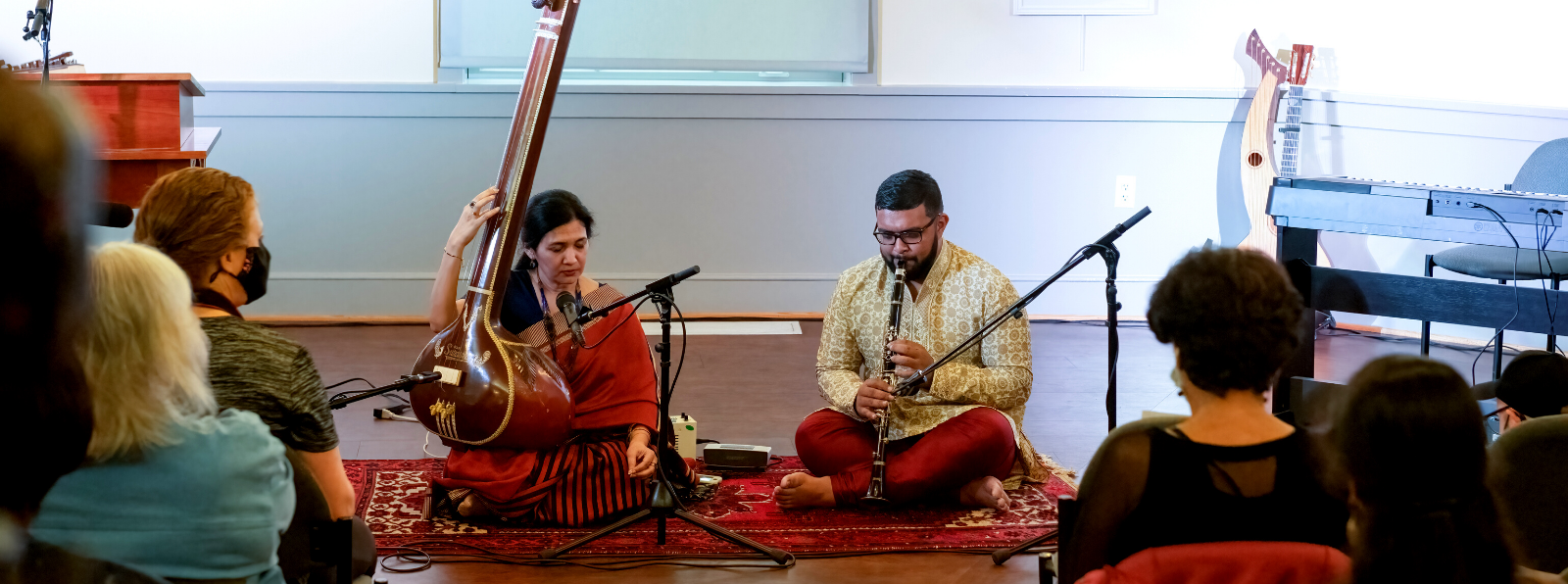 A crowd watching a performance of two musicians sitting.