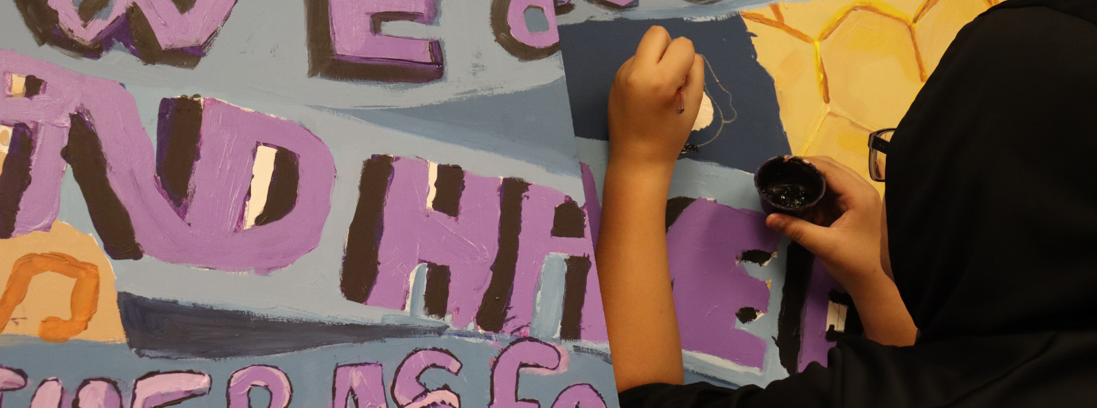 A person is painting a mural that includes text.