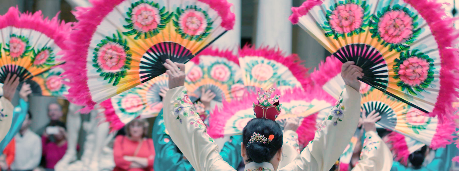 A group holds up hand fans during a performance.