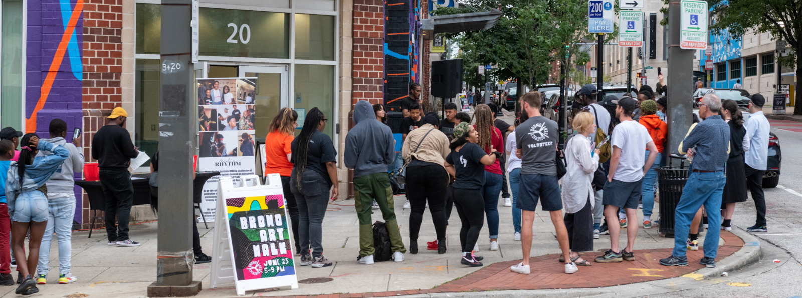 A large group of people stand on a sidewalk.