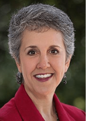 Smiling woman with short, grey hair and a red coat.