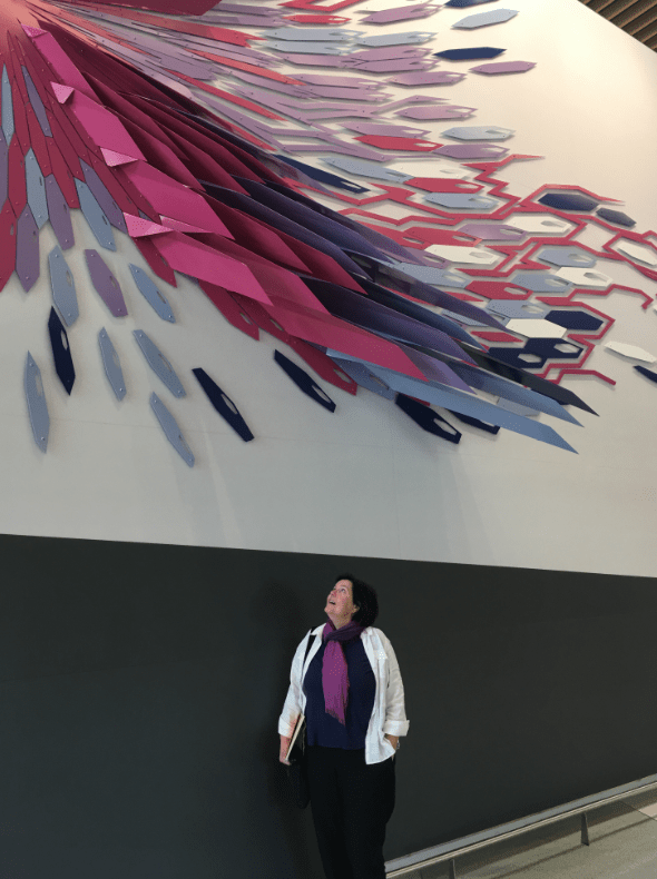 Woman standing in front of a colorful mural