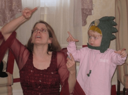 Kathy MacMillan teaches the ASL sign SUN alongside a young volunteer playing the part of a dragon in an interactive story.